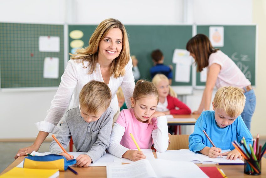 freundliche lehrerin mit kindern in der grundschule